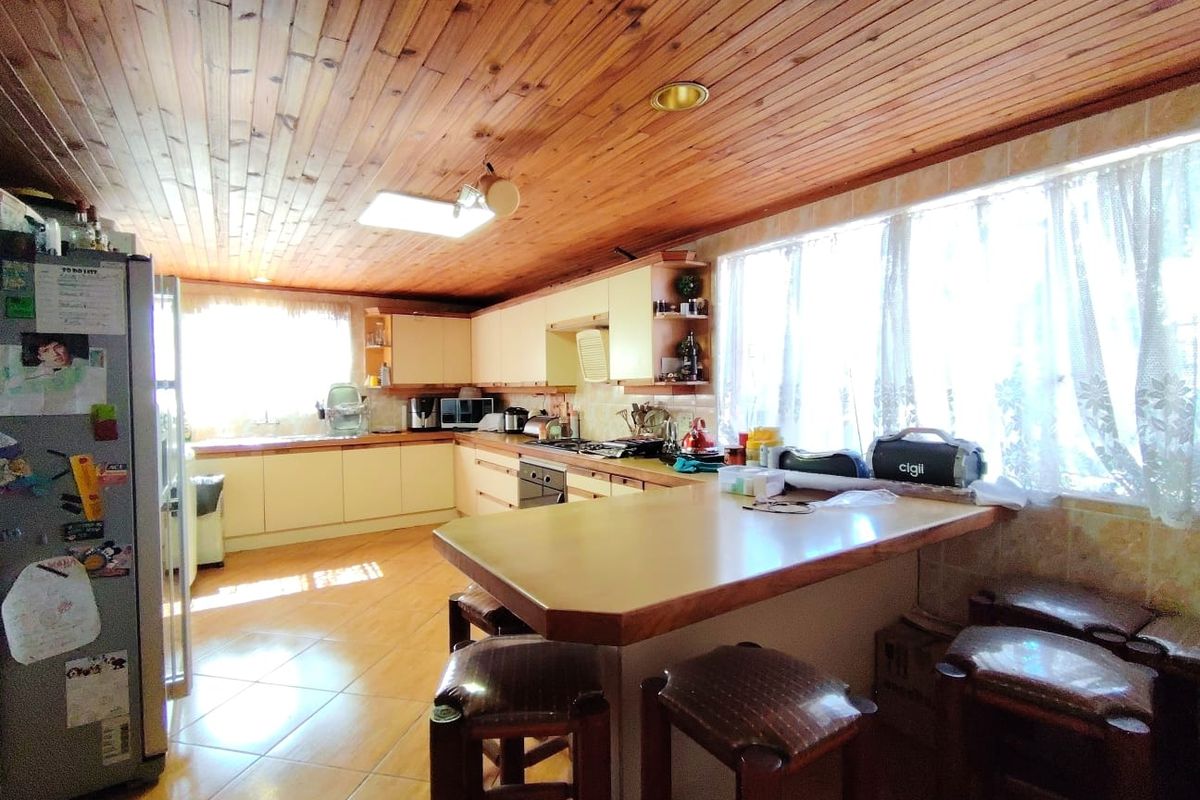 Spacious kitchen featuring timber ceiling, tiled flooring, built-in cabinetry, and a functional breakfast bar area with ample natural light.