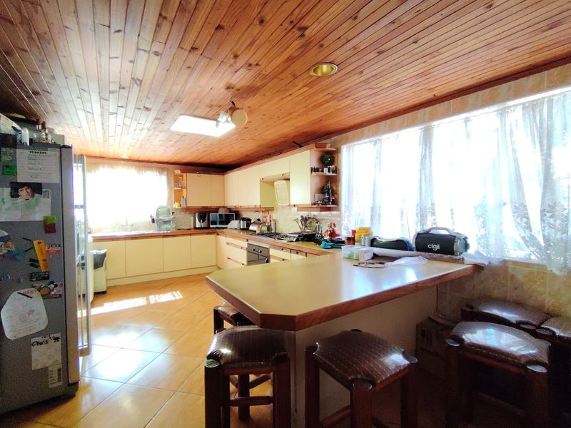 Spacious kitchen featuring timber ceiling, tiled flooring, built-in cabinetry, and a functional breakfast bar area with ample natural light.