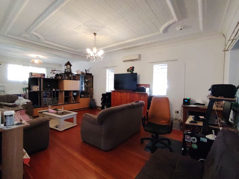 Spacious living room featuring original ornate plaster ceiling detailing, polished hardwood flooring, and a wall-mounted split-system air conditioner.