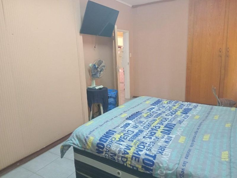 A bedroom featuring tiled flooring and a built-in wooden wardrobe, providing functional storage space.