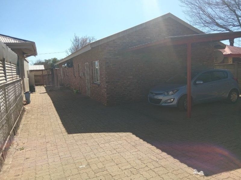 Side view of the property featuring a face brick exterior, paved driveway, and a covered carport area.