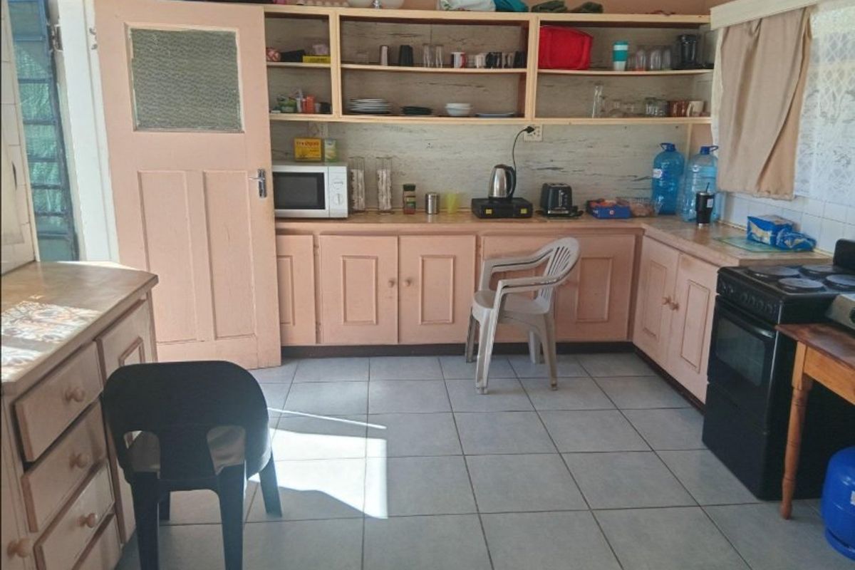 A functional kitchen featuring tiled flooring, built-in cabinetry with open shelving, and a freestanding oven, offering potential for cosmetic updates.