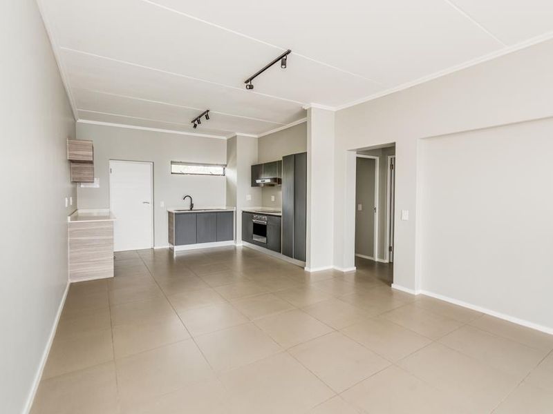 Spacious open-plan living area featuring a modern kitchen with built-in cabinetry, integrated oven, extractor fan, and neutral tiled flooring throughout.