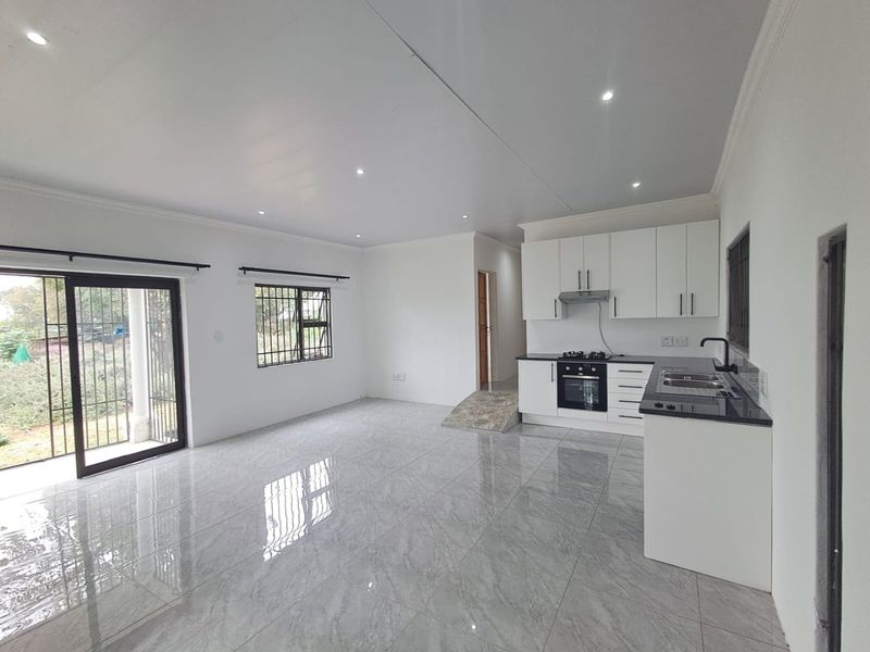 Modern open-plan living area featuring a sleek kitchen with granite countertops, built-in appliances, and large sliding doors leading to the exterior.
