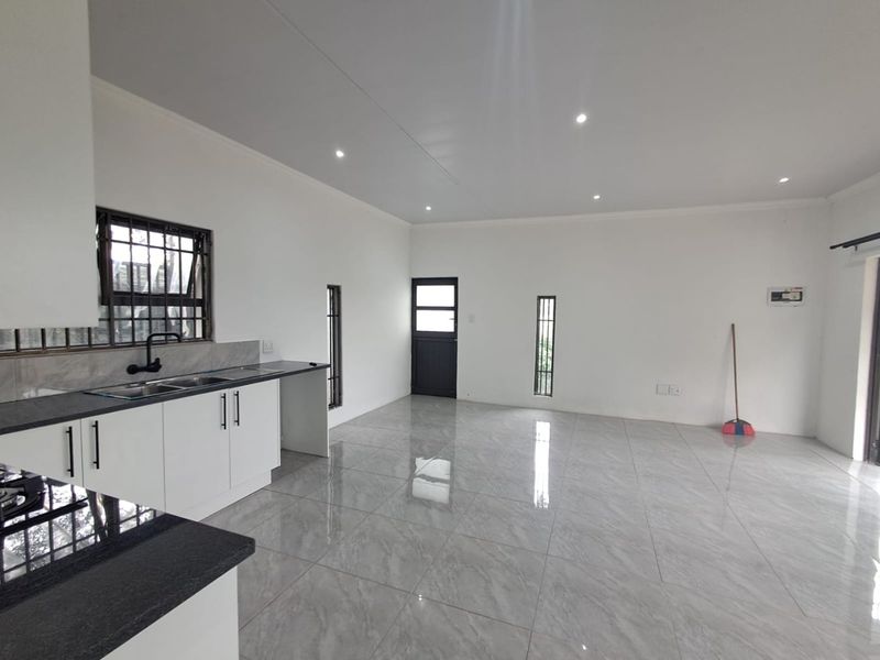 Spacious open-plan living area featuring a modern kitchen with granite countertops, sleek white cabinetry, and polished porcelain floor tiles throughout.