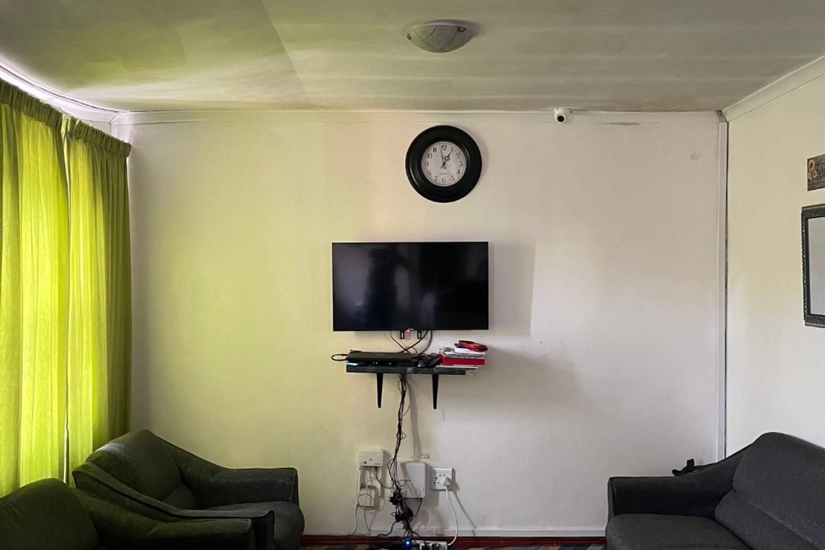 A living room featuring a central wall-mounted television area with visible electrical wiring and basic ceiling finishes.