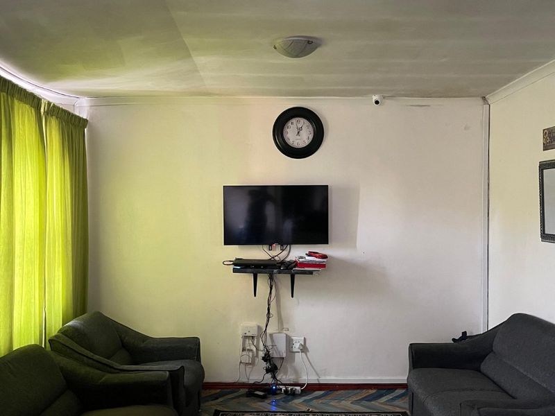 A living room featuring a central wall-mounted television area with visible electrical wiring and basic ceiling finishes.