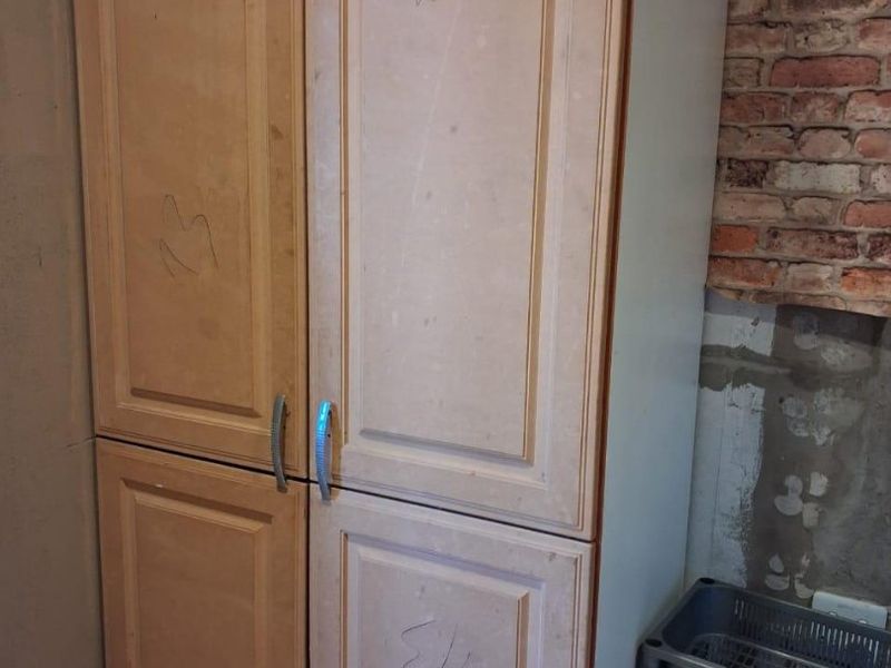 A kitchen area featuring built-in cabinetry and an exposed brick wall, currently requiring finishing and cosmetic repairs to the surrounding wall surfaces.