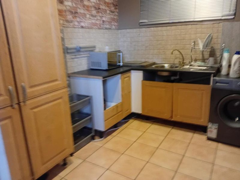 A compact kitchen featuring wooden cabinetry, tiled backsplash, and ceramic flooring, currently showing signs of wear and missing cabinet components.