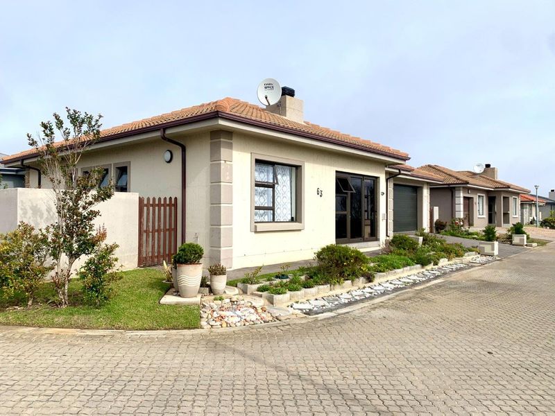 A well-maintained single-story residential property featuring a tiled roof, paved driveway, integrated garage, and neat front garden landscaping.