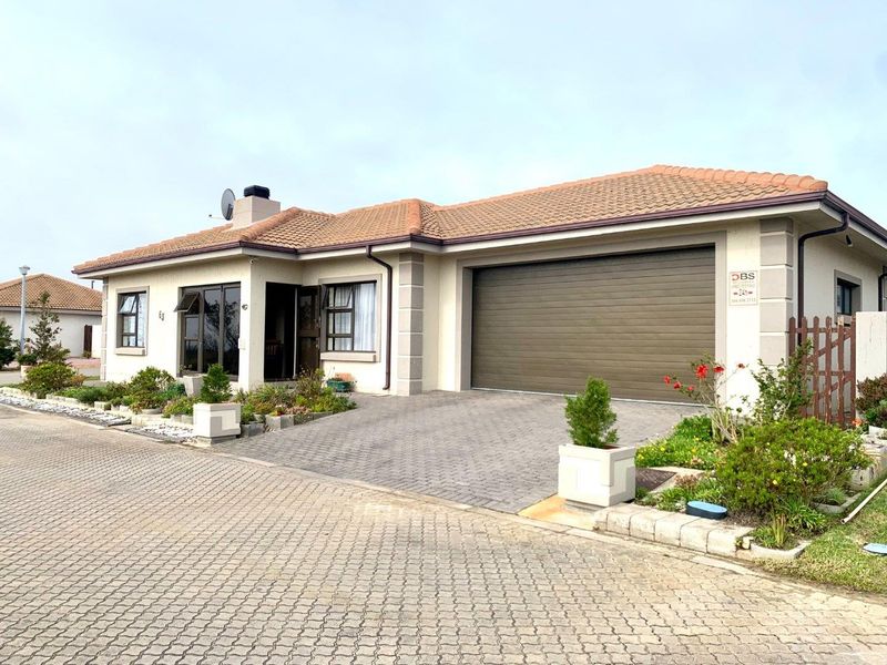 Front elevation of a single-story residential house featuring a paved driveway, automated garage, and tiled roof.