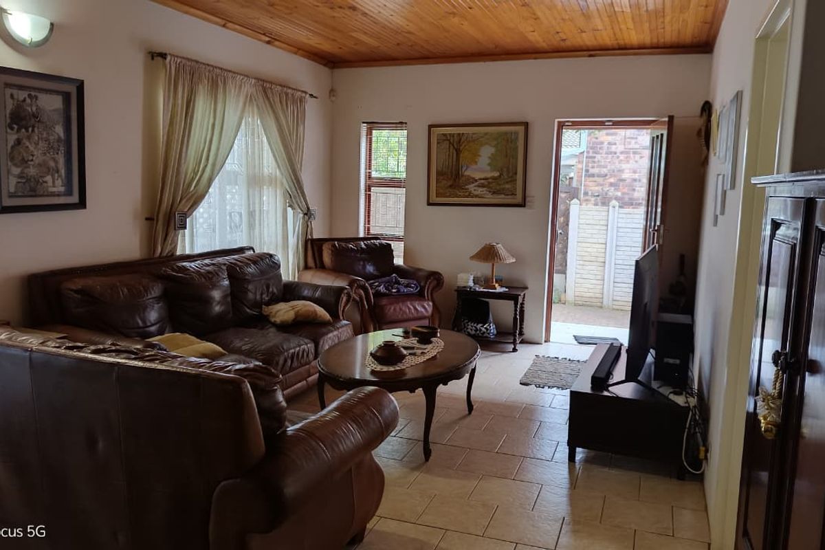 A living room featuring tiled flooring and a timber-paneled ceiling, with direct access to an outdoor area.