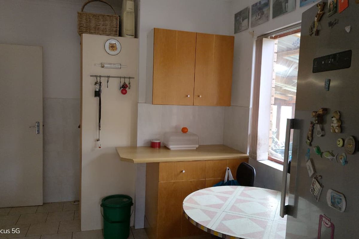 A dated kitchen area featuring laminate cabinetry, tiled splashbacks, and tiled flooring, offering potential for a modern renovation.
