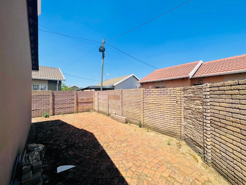 A private rear courtyard featuring a paved surface and enclosed by a solid brick boundary wall.