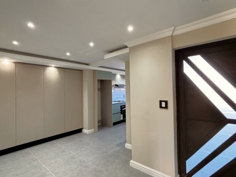 Modern entrance hall featuring sleek built-in cabinetry, recessed downlighting, tiled flooring, and a contemporary feature front door leading into the home.