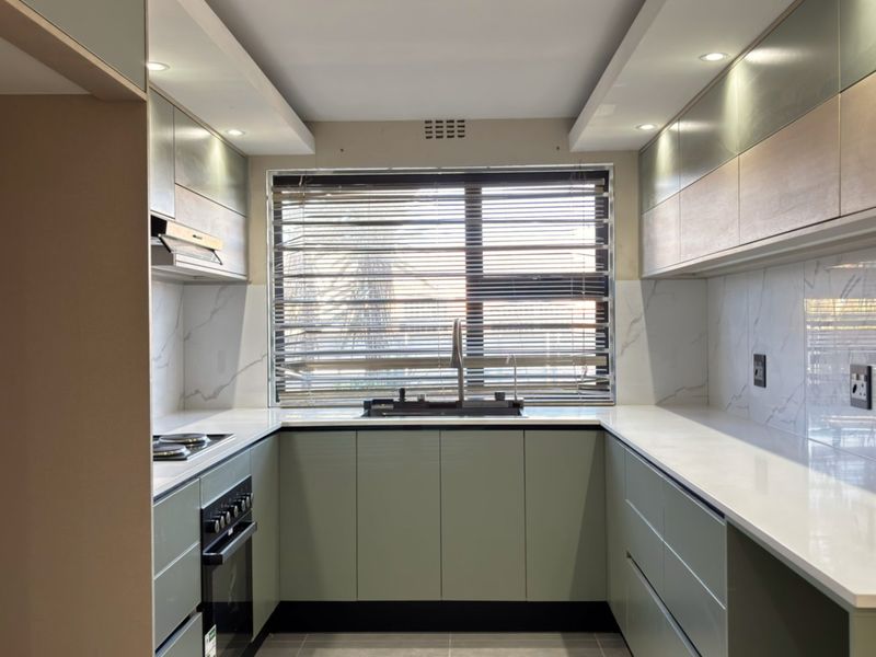 Modern U-shaped kitchen featuring sleek cabinetry, stone countertops, marble-look splashbacks, and integrated appliances, offering a clean and contemporary culinary space.