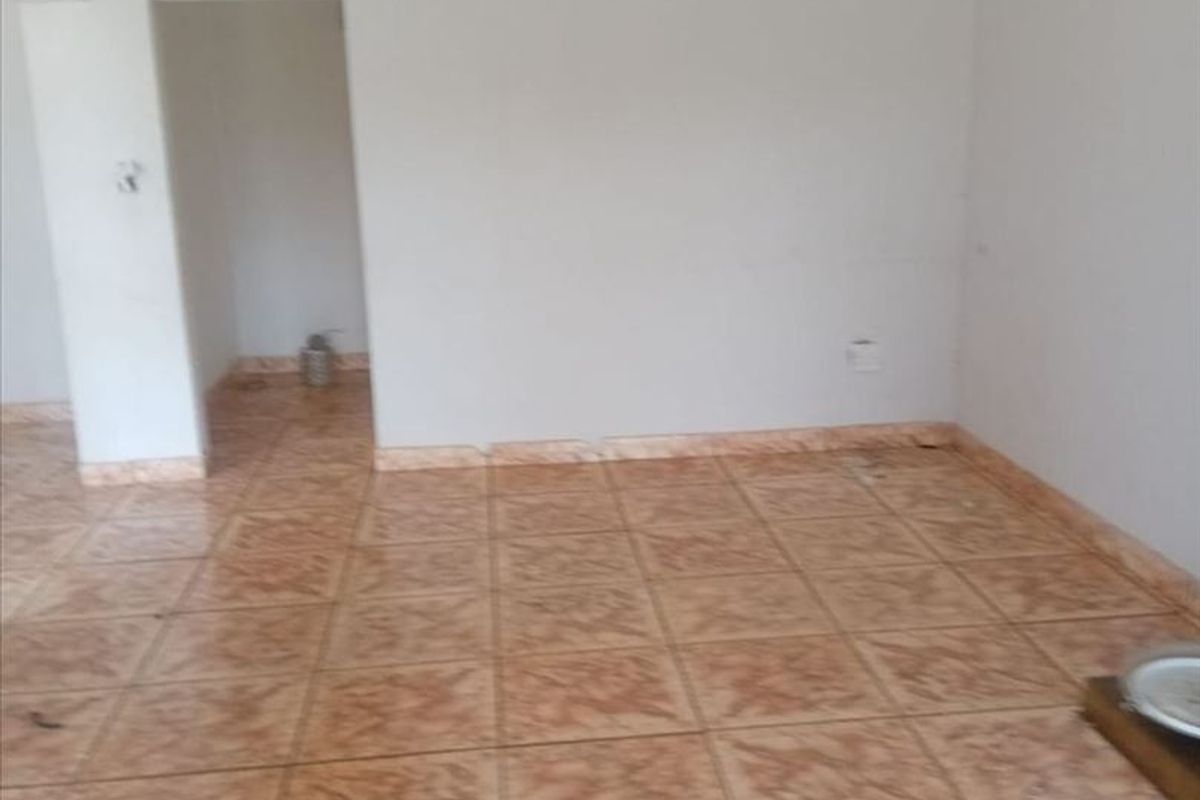 An empty living room featuring ceramic floor tiles and coved ceiling cornicing, providing a blank canvas for interior design updates.