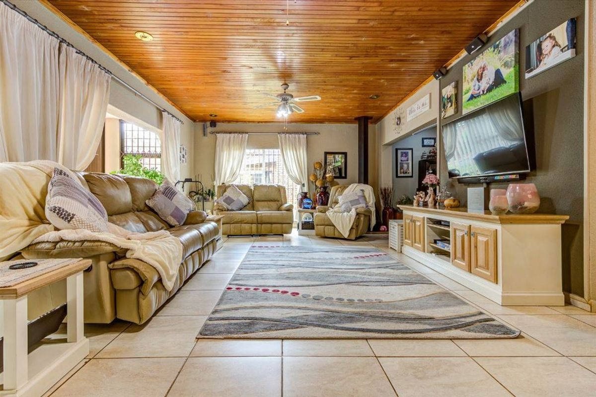 Spacious living room featuring a warm timber-clad ceiling, tiled flooring, a freestanding fireplace, and built-in media cabinetry.