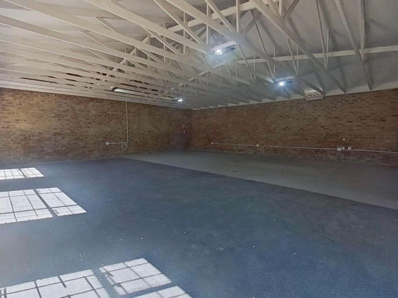 A large, open-plan utility space featuring exposed brick walls, timber roof trusses, and concrete flooring, suitable for various commercial or storage applications.