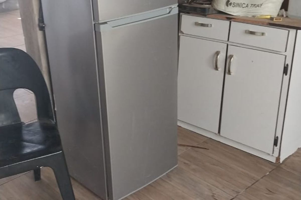 A functional kitchen area featuring base cabinetry and tiled flooring, currently requiring cosmetic updates and wall finishing.