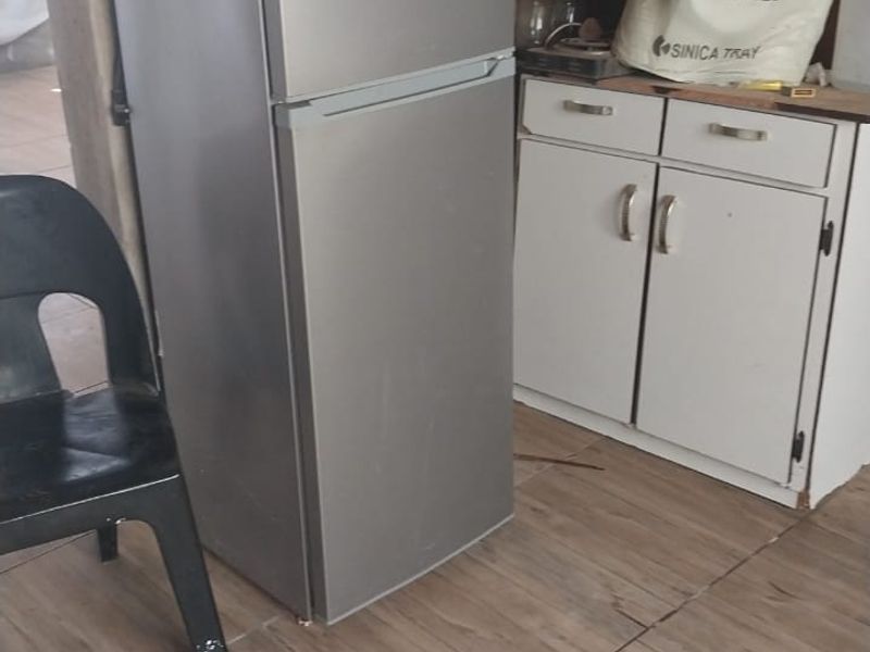 A functional kitchen area featuring base cabinetry and tiled flooring, currently requiring cosmetic updates and wall finishing.