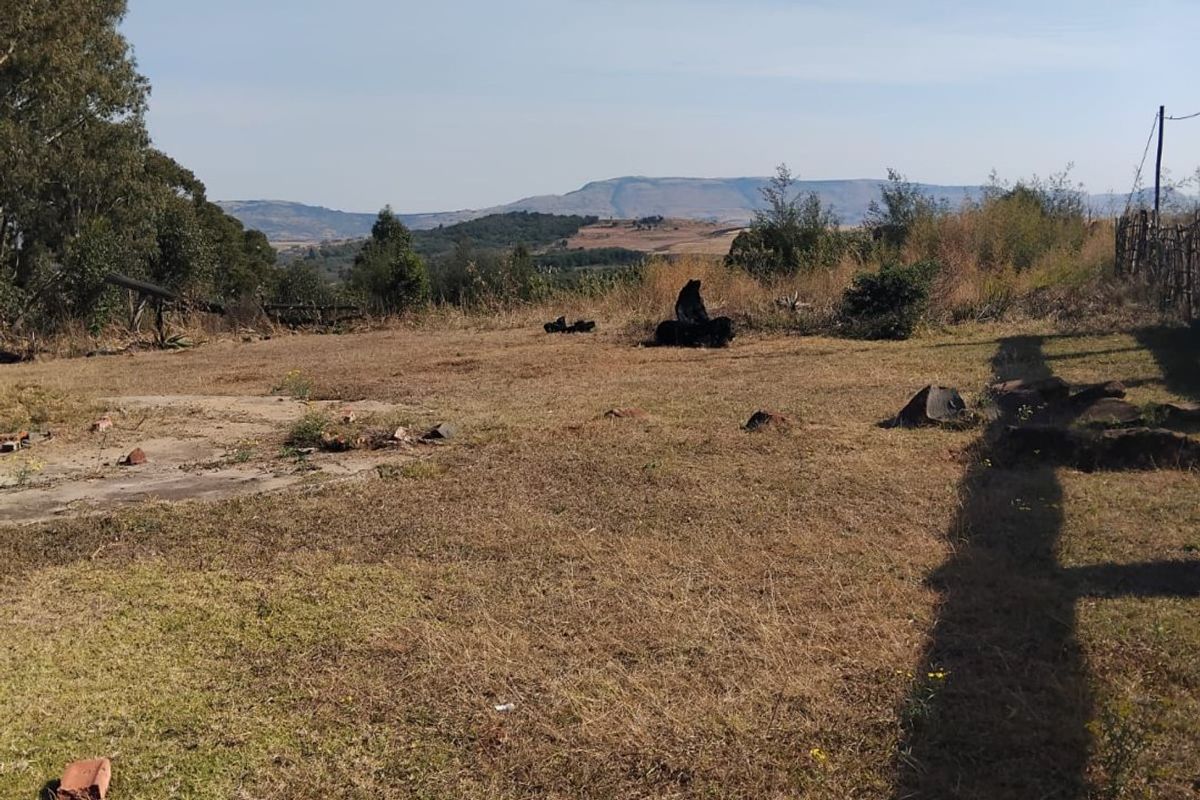 A wide-angle view of the vacant residential land featuring natural landscape and distant mountain scenery.