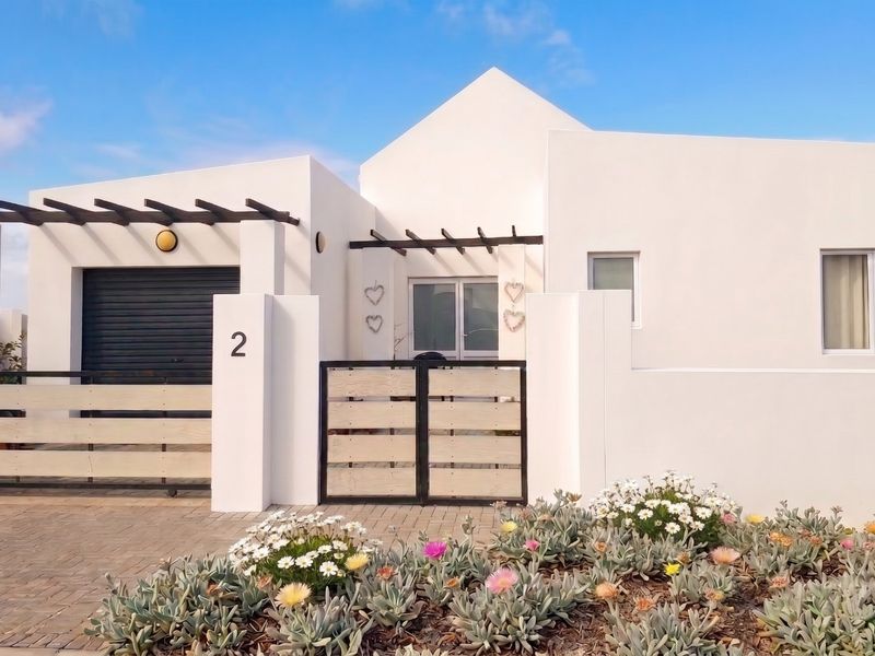 Modern front facade featuring a clean white finish, timber pergola accents, paved driveway, and secure gated entrance.