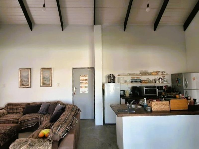 Open-plan living area featuring high vaulted ceilings with exposed beams, a functional kitchen island, and integrated storage space.