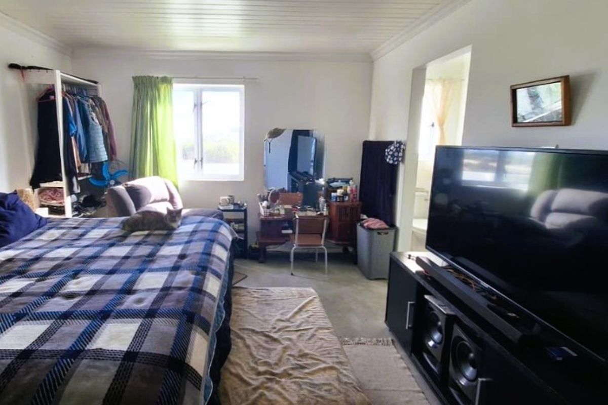 A bedroom featuring a timber ceiling and natural light from a window, providing a functional space for rest.