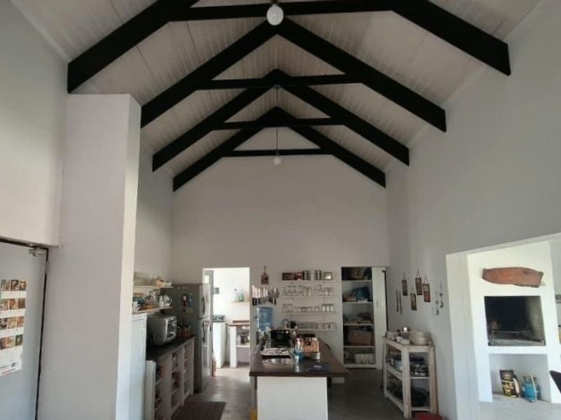 Spacious open-plan living area featuring a high vaulted ceiling with exposed black timber trusses and a built-in fireplace.