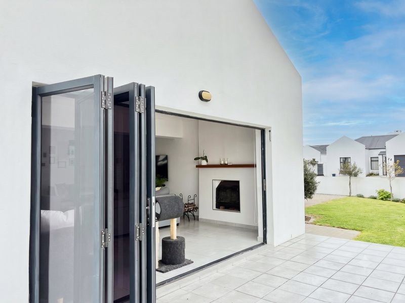 A modern patio area featuring large bi-fold doors opening into a living space with a built-in fireplace and tiled flooring.