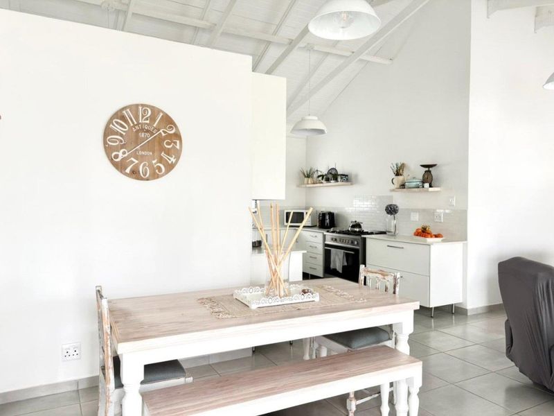 Bright open-plan kitchen and dining area featuring a vaulted ceiling, modern cabinetry, subway tile backsplash, and tiled flooring.