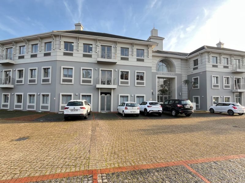 A professional exterior view of a multi-story commercial building, The Pavilion, featuring a paved parking area and multiple balconies.