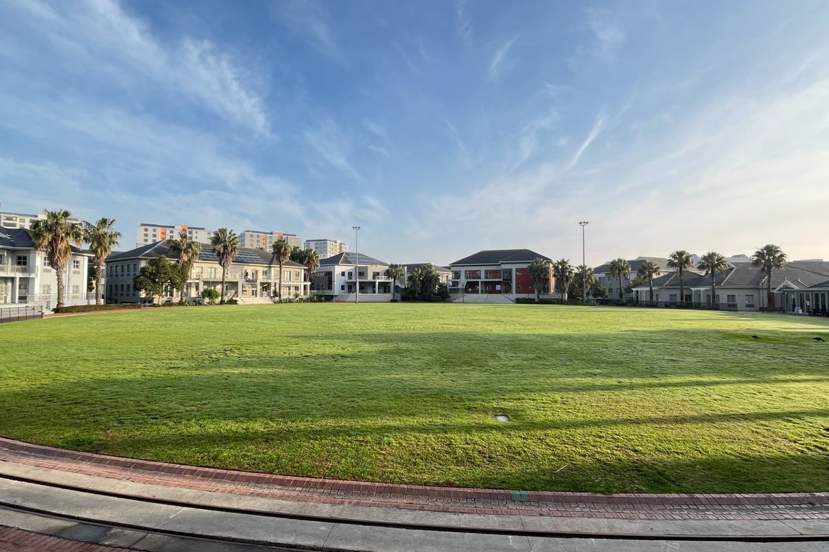 A wide-angle view of a large, well-maintained central lawn area surrounded by multi-story commercial office buildings and paved walkways.