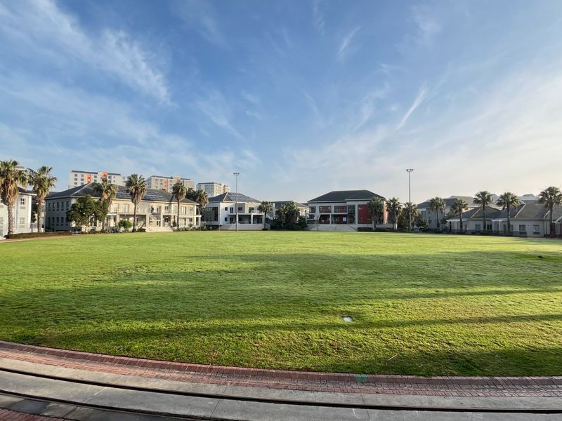 A wide-angle view of a large, well-maintained central lawn area surrounded by multi-story commercial office buildings and paved walkways.