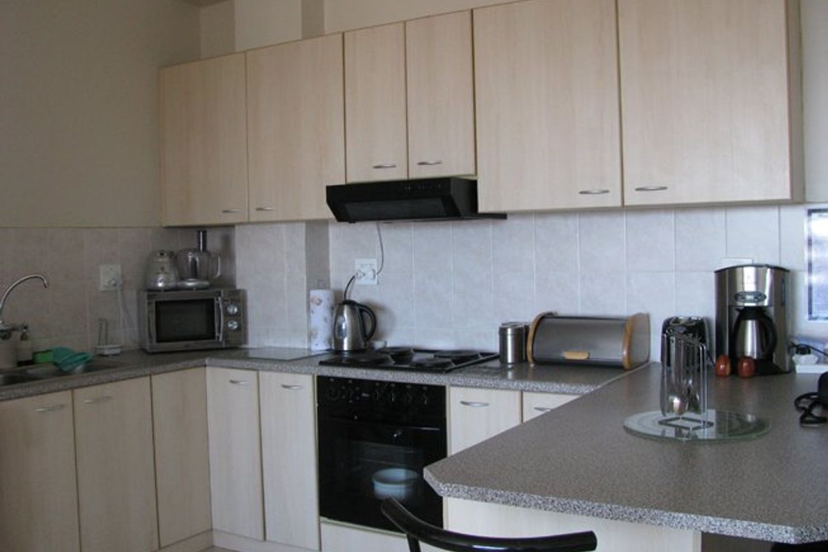 A functional kitchen featuring light wood-tone cabinetry, laminate countertops, a built-in oven with gas hob, and a tiled backsplash.