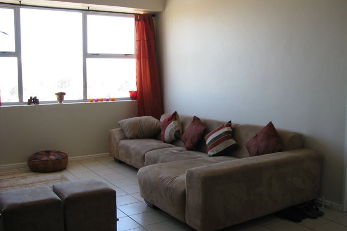 A living room featuring tiled flooring and a large window that provides natural light.