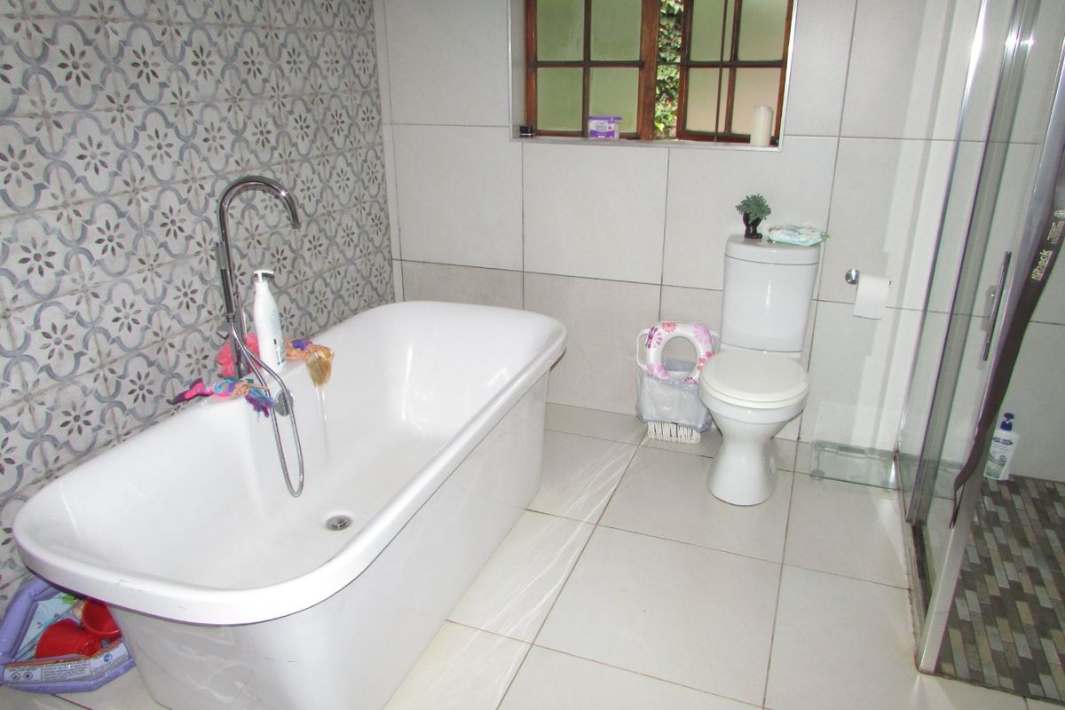 A modern bathroom featuring a freestanding bathtub with floor-mounted mixer, a separate shower enclosure, and a combination of neutral and patterned feature wall tiles.