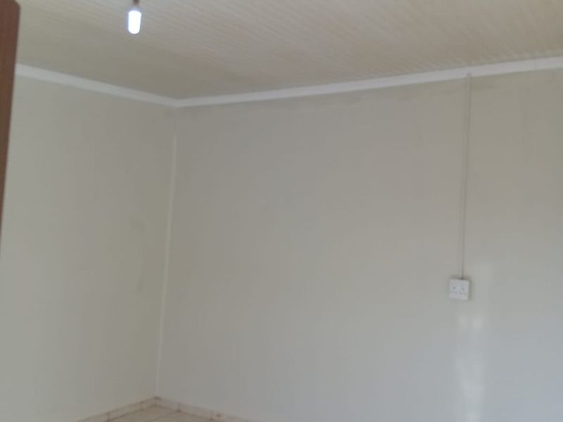An empty bedroom featuring tiled flooring and a coved ceiling with basic lighting.