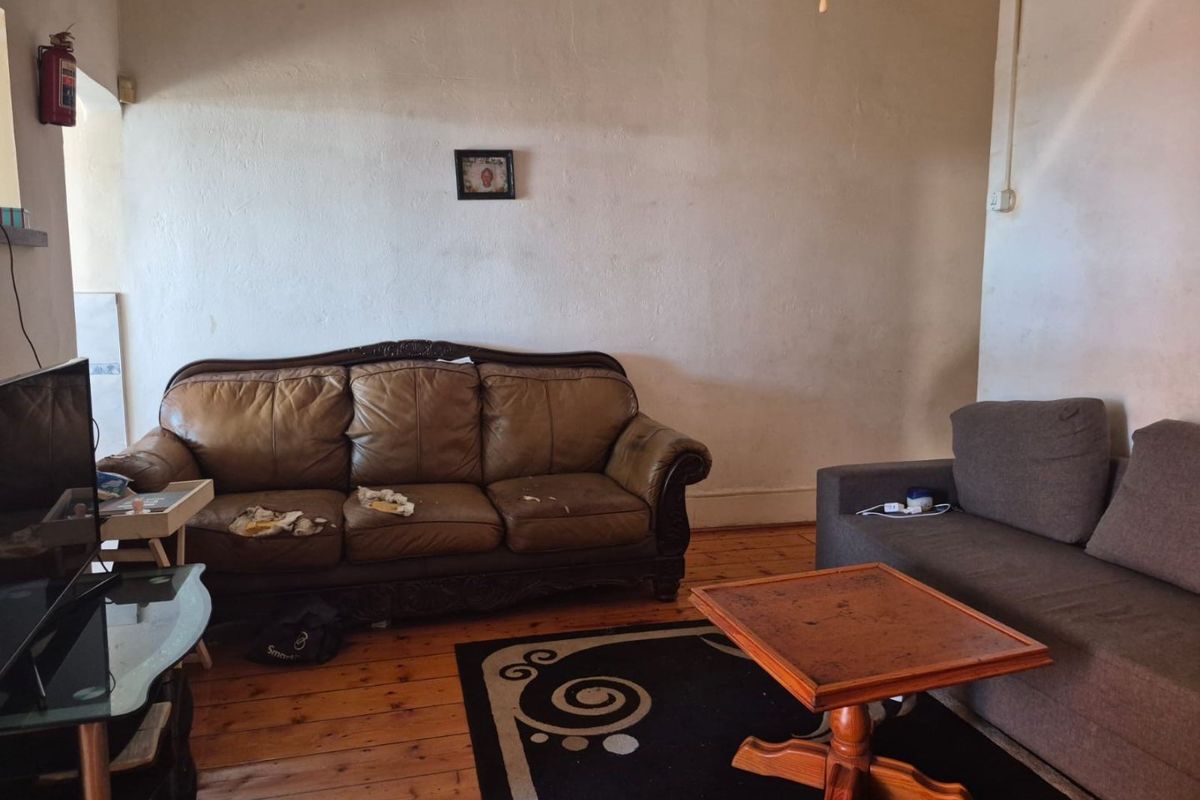 A living room featuring original timber flooring and plain wall finishes, providing a functional space with potential for cosmetic updates.