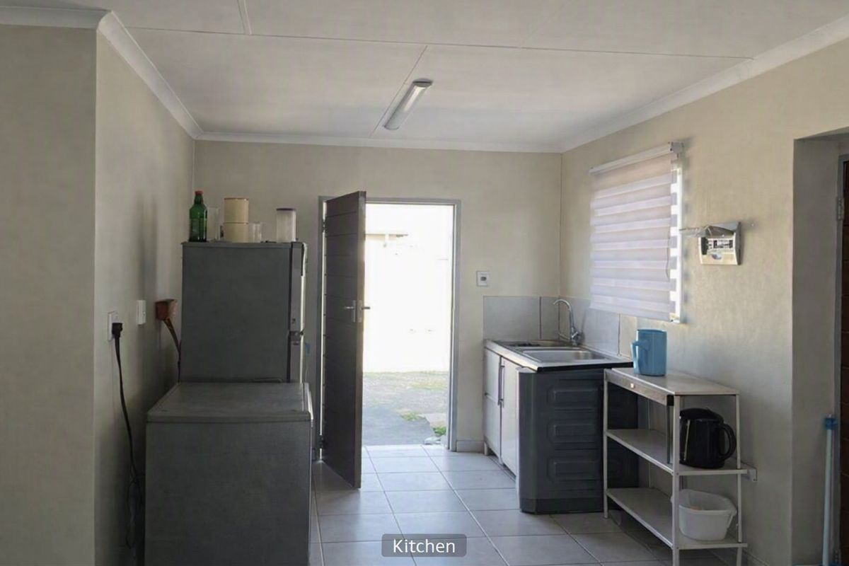 A functional kitchen area featuring tiled flooring, a single sink unit, and direct access to the exterior.