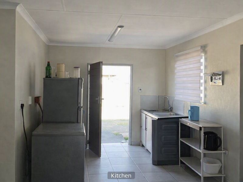 A functional kitchen area featuring tiled flooring, a single sink unit, and direct access to the exterior.