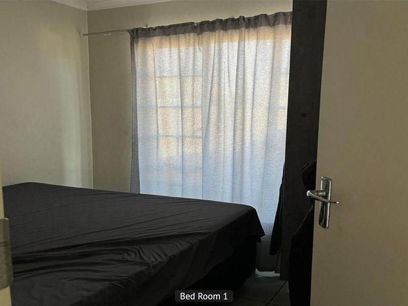 A standard bedroom featuring neutral wall tones and a window with installed curtain rod, viewed from the doorway.
