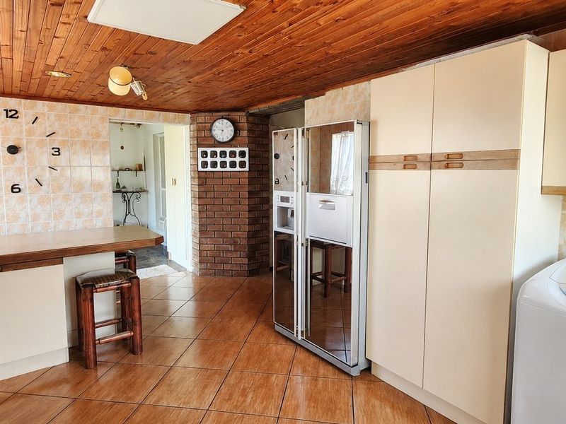 A functional kitchen featuring timber ceilings, tiled splashbacks, an exposed brick pillar, and built-in cabinetry with a breakfast bar.