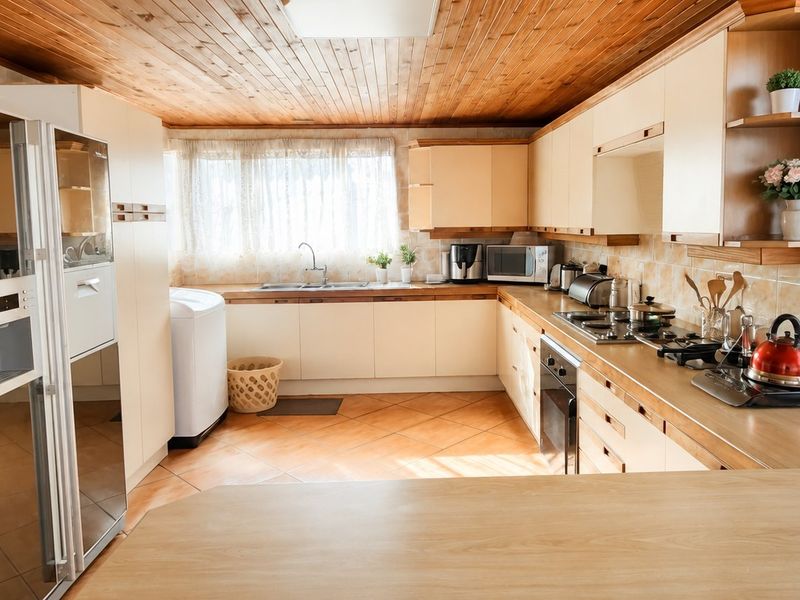 A functional kitchen featuring timber ceiling paneling, ample built-in cabinetry, a gas hob, built-in oven, and tiled flooring.