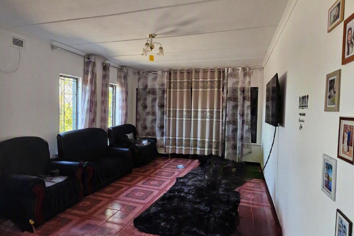 A living room featuring tiled flooring, ceiling lighting, and wall-mounted television infrastructure, offering a functional space ready for cosmetic updates.