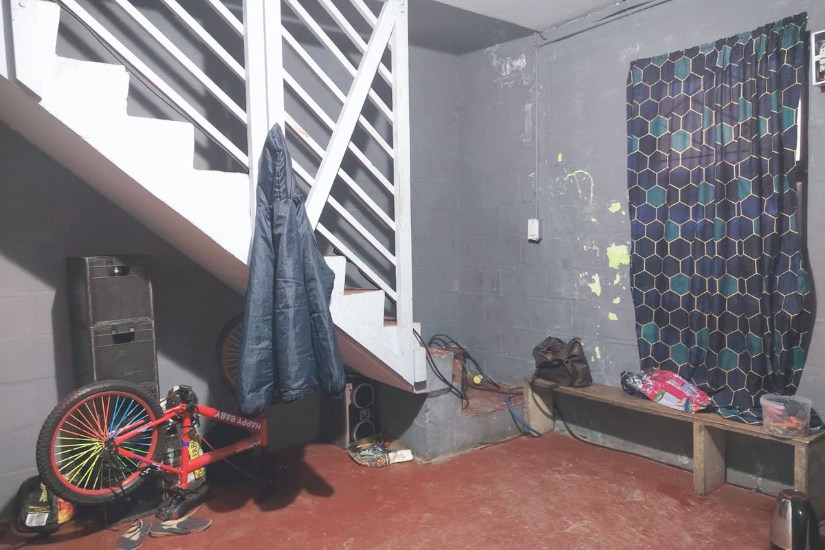 A functional garage space featuring a staircase, exposed blockwork walls, and a painted concrete floor, offering potential for storage or utility use.