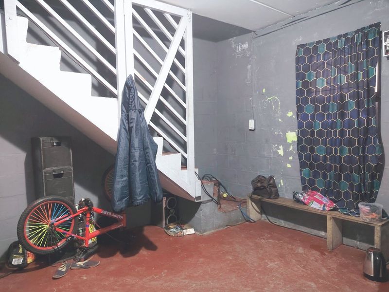A functional garage space featuring a staircase, exposed blockwork walls, and a painted concrete floor, offering potential for storage or utility use.