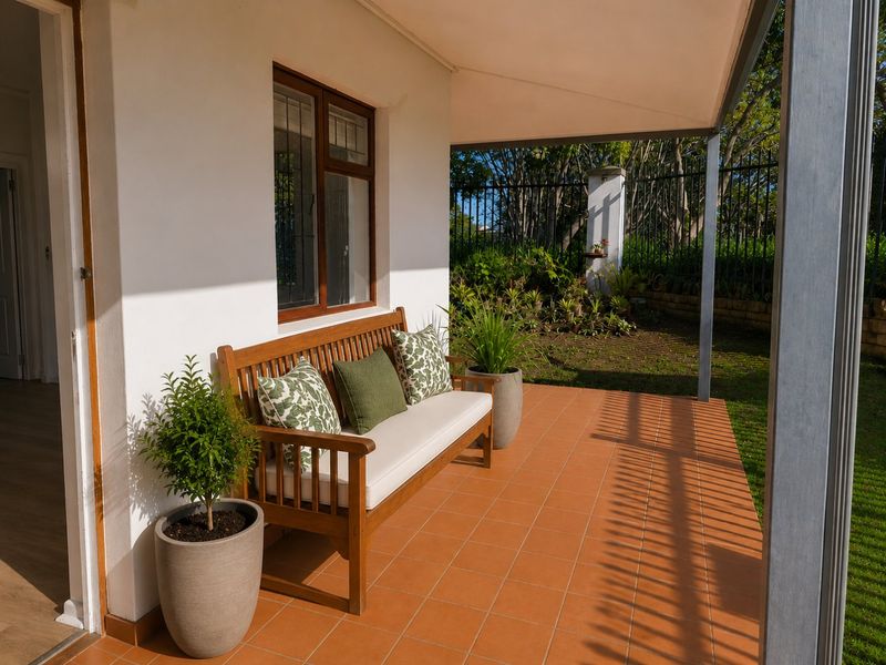 A covered patio area featuring terracotta floor tiles, providing a seamless transition to the garden space.