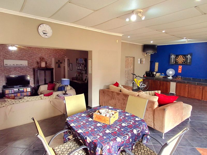 Spacious open-plan living and dining area featuring tiled floors, an exposed brick accent wall, and built-in cabinetry, offering a versatile layout for family living.